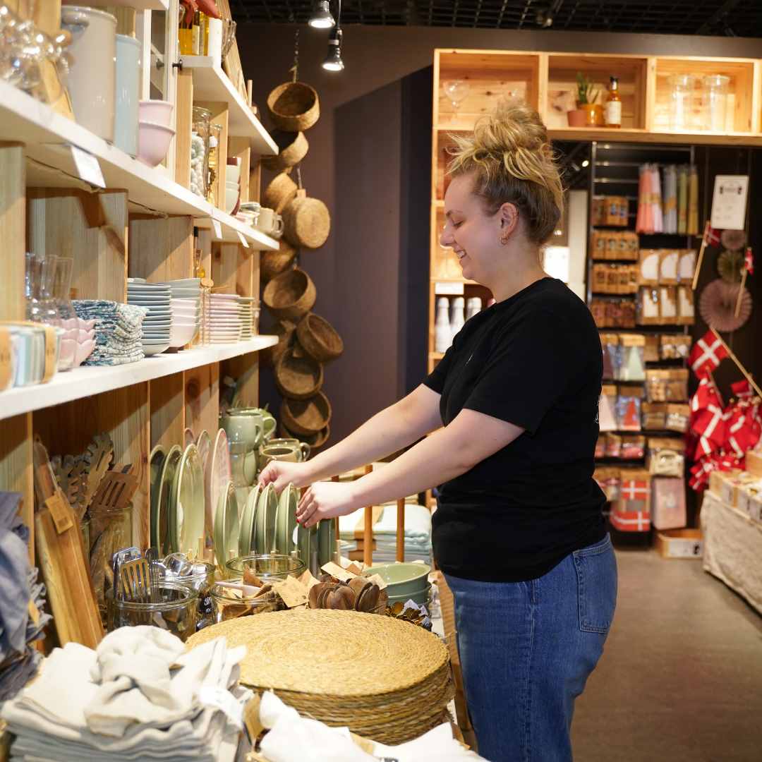 Medarbejder sætter tallerkener på hylderne i Søstrene Grene i Randers.